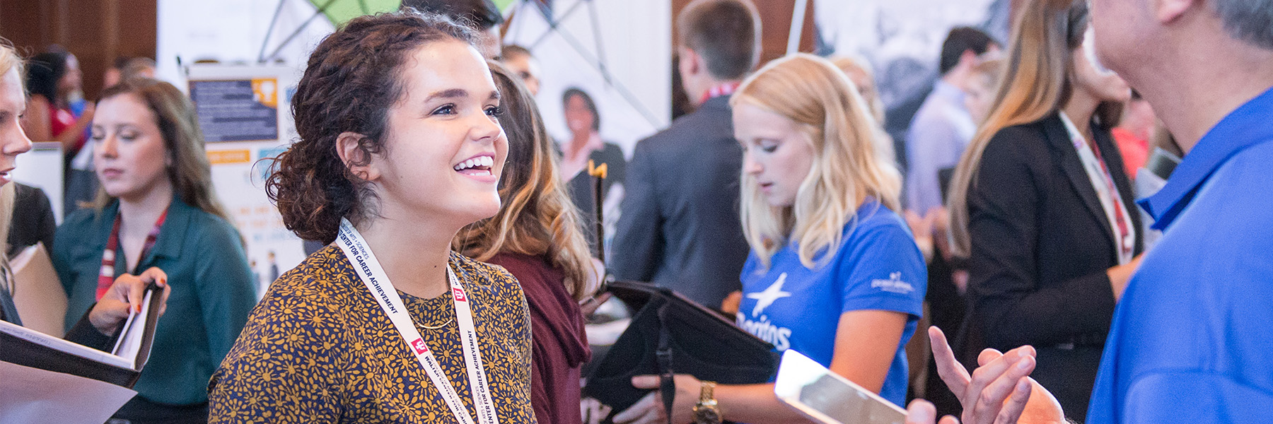 Student smiling as she talks to an employer at a career fair