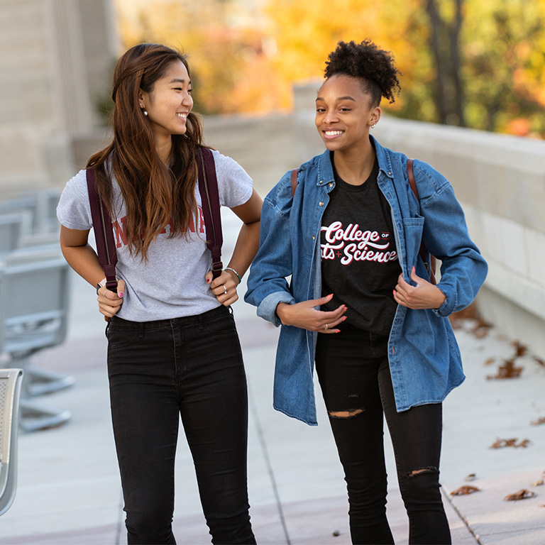 Two students smiling as they walk through campus