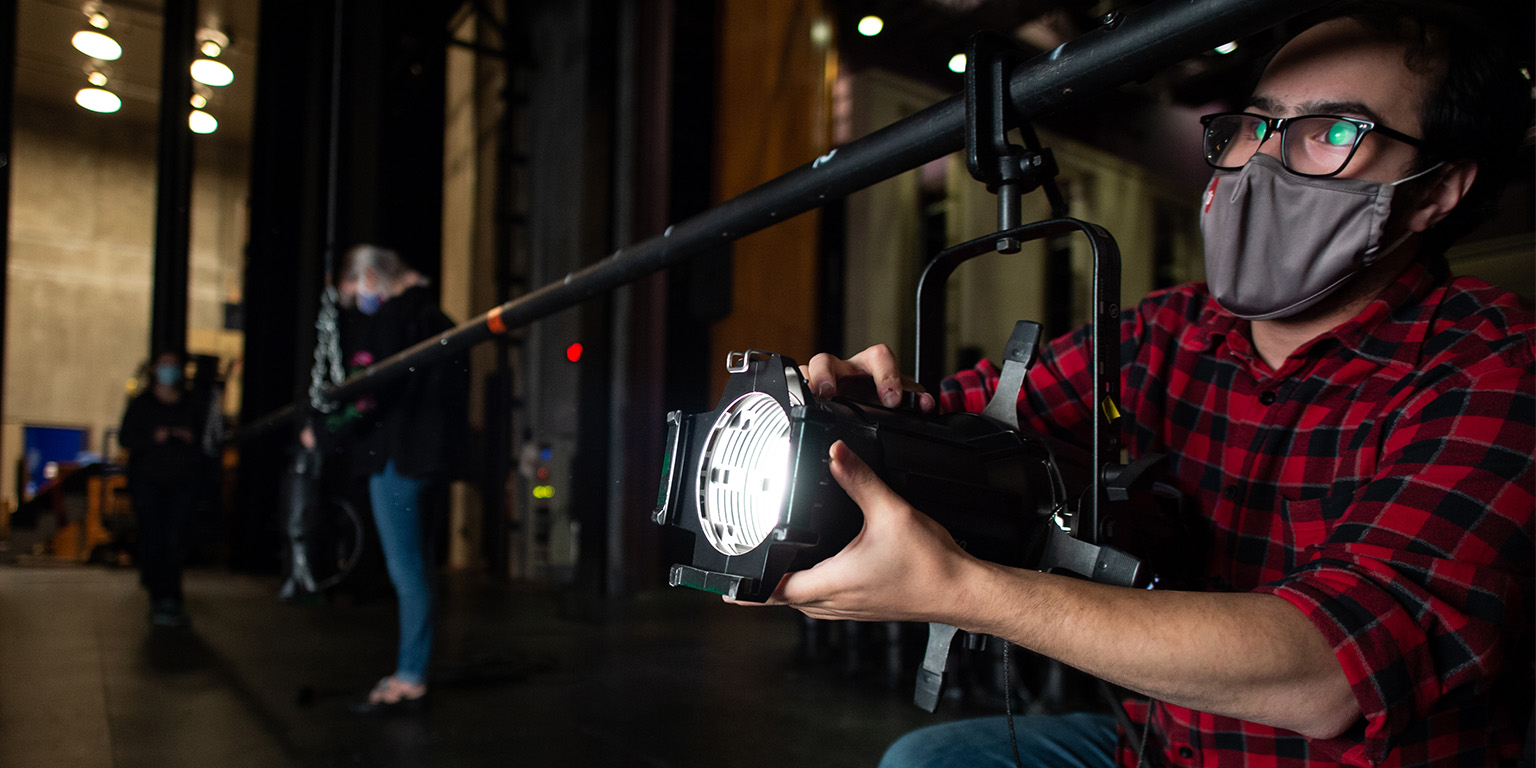 A student operating a stage light