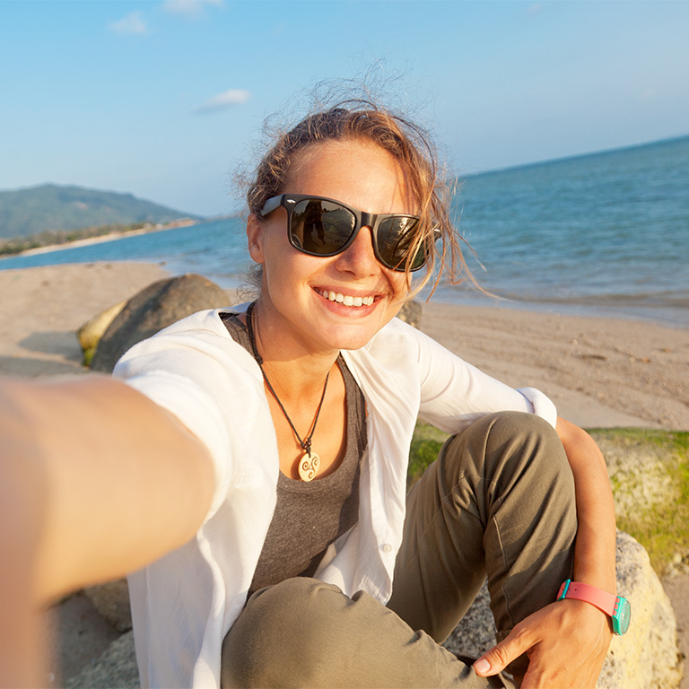 A student smiling in a selfie on the beach